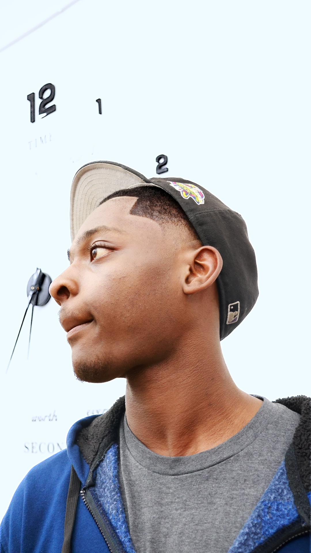 Profile — side angle, cap turned back, clock background
